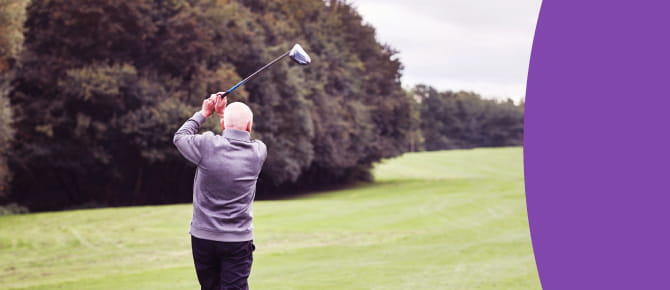 Man hits a ball on a golf course.