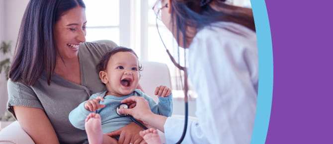 Person holding child, doctor listening to child's heart with stethoscope