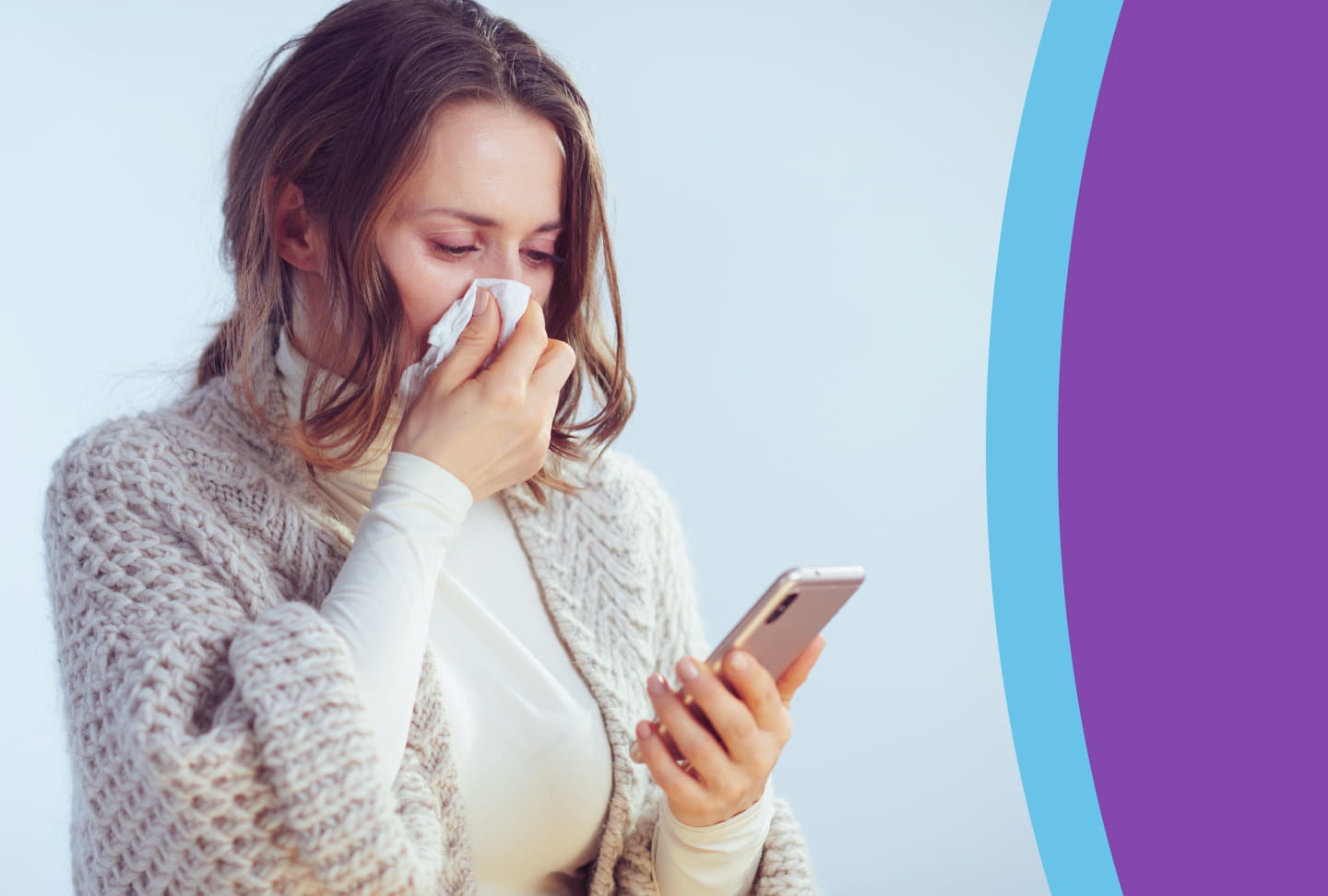 Person blowing nose with tissue, looking at phone