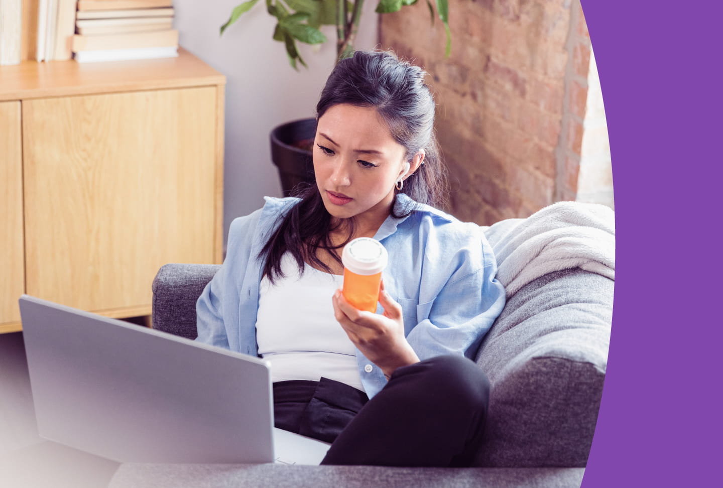 Person sitting with laptop, holding medication bottle