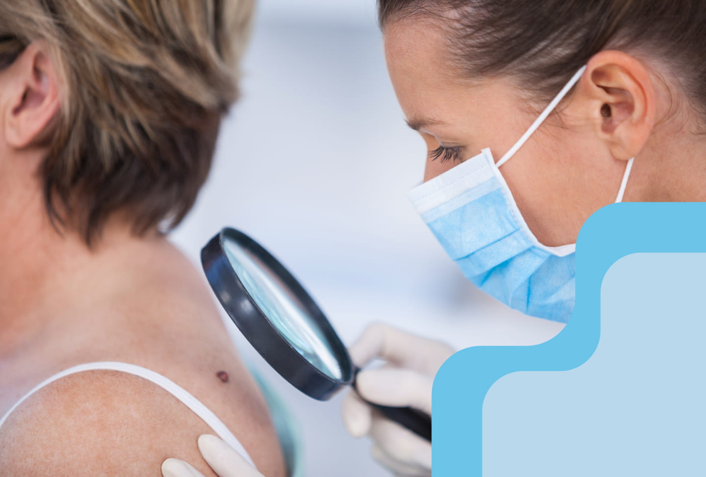 Physician holding a magnifying glass examining a patient's back.