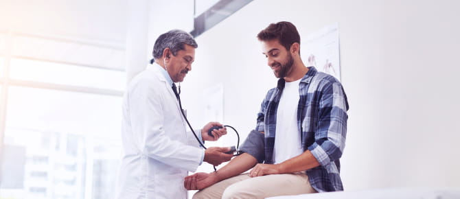A man's physician checks his blood pressure.